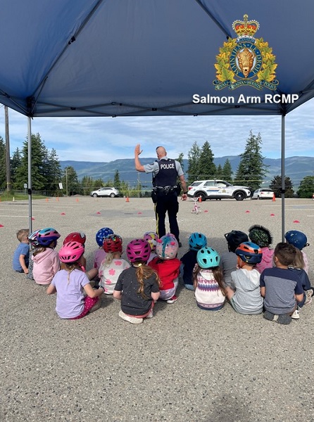 Salmon Arm RCMP member demonstrating hand signals to a local preschool class during their bike road