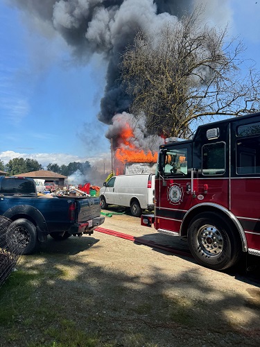 Picture of barn on fire with a firetruck