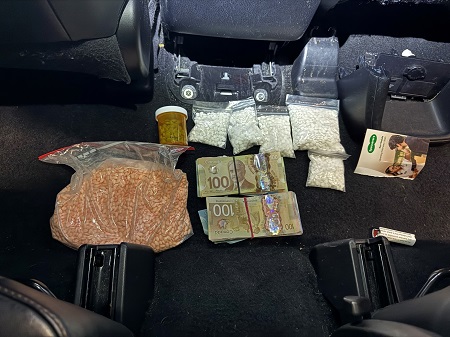 Five bags of white pills, one larger bag of pink pills, a bottle of blue pills and two bundles of Canadian cash.