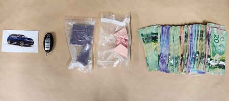 Seized evidence laid out on a table, including a photo of an SUV, a vehicle fob, two bags of drugs and several thousand dollars of Canadian cash.