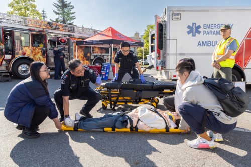 Students assisting EHS with loading a stretcher into an ambulance
