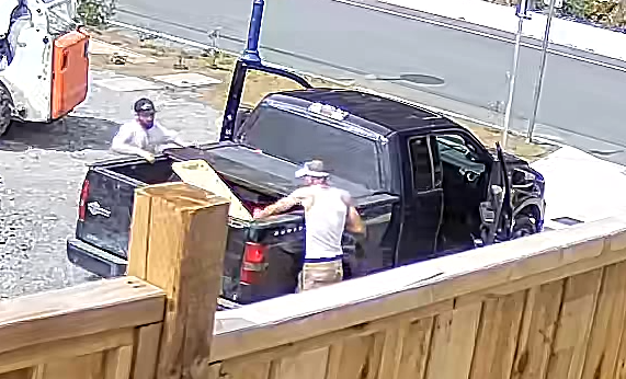 Photo of both suspects reaching into the cargo box of the black truck