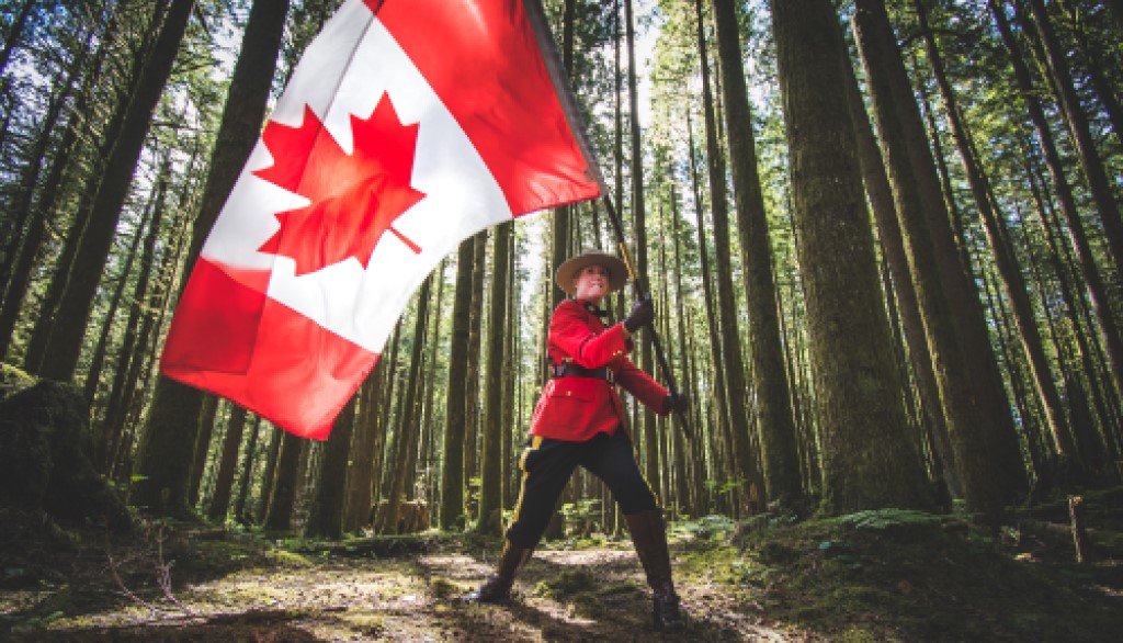 Police officer in red serge waving the Canadian flag