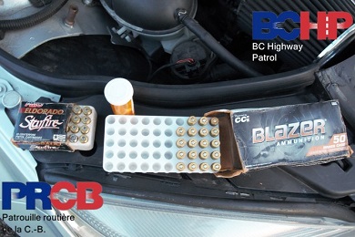 Photo de deux bo&icirc;tes de munitions avec le compartiment moteur du v&eacute;hicule en arri&egrave;re-plan