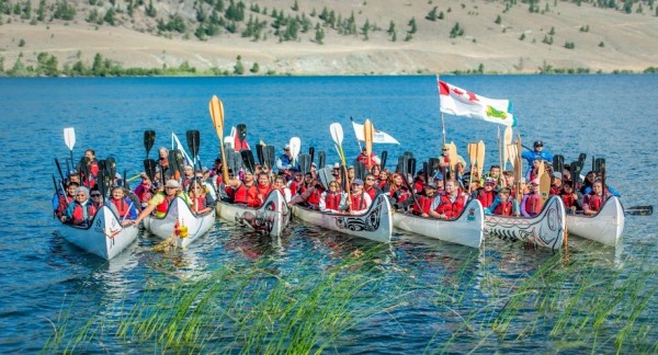 6 canoes with paddlers oars in the air