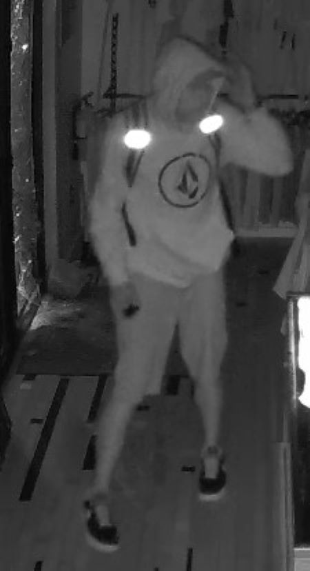 Suspect en short : Image de s&eacute;curit&eacute; par vision nocturne d&rsquo;un suspect v&ecirc;tu d&rsquo;un chandail, d&rsquo;un short et portant un sac &agrave; dos. Le chandail comporte un logo &agrave; l&rsquo;int&eacute;rieur d&rsquo;un cercle.