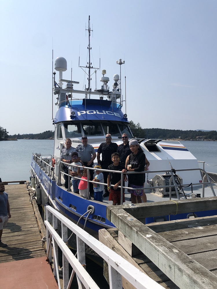 The RCMP police boat Higitt at dock with several smiling police officers and boys on the deck