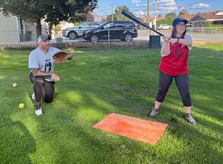 Cst. Phil Whiles catches a softball behind the plate as Special Olympian Kristin White takes a swing for it during a recent practise session. 