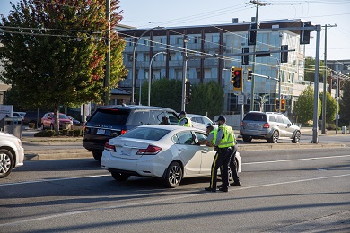 Uniformed Officers approach two vehicles stopped at a red light