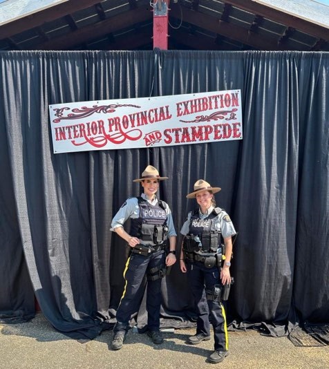 Les gendarmes Valotaire et Taylor, agentes de la GRC, posent devant une banni&egrave;re de l&rsquo;Exposition provinciale int&eacute;rieure.