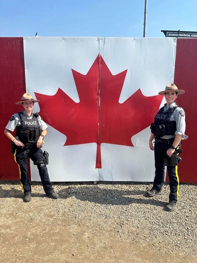 Des agentes de la GRC posent devant un drapeau canadien &agrave; l&rsquo;Exposition provinciale int&eacute;rieure de 2023.