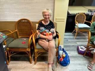 Photo of woman sitting in a chair holding knitted bear