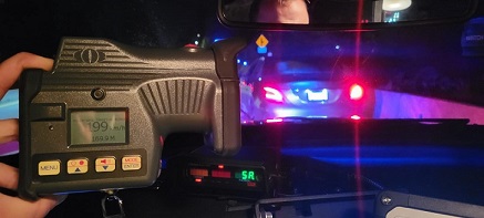 Picture of a vehicle pulled over by an officer while he is holding a laser device with reading of 199 km/h 169.9 M