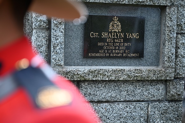 Cst. Shaelyn Yang&rsquo;s name on a black plaque on a stone cairn beside an RCMP officer wearing Red Serge