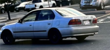 An older model grey, four-door Honda Civic.