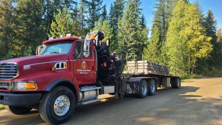 Une photo de profil d&rsquo;un gros tracteur semi-remorque rouge. Un d&eacute;calque &laquo; Kamloops Hiab Services &raquo; se trouve sur la porti&egrave;re du c&ocirc;t&eacute; du conducteur. 