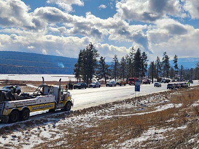 Long lines of tow trucks, maintenance vehicles, fire trucks, and police vehicles with lights flashing on both sides of the highway.