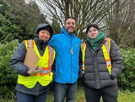 Photo of three community volunteers and partners holding clipboards and smiling