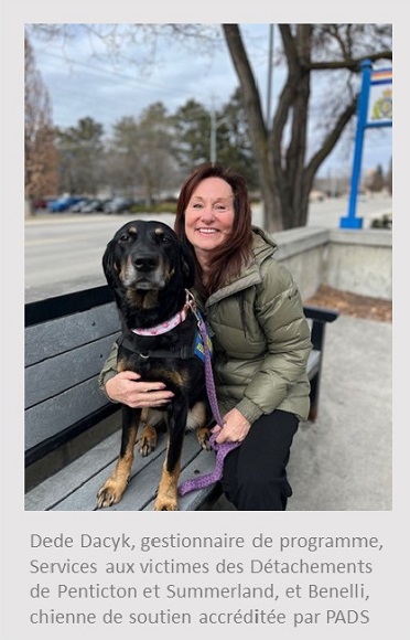 Photo d&rsquo;une femme blanche assise sur un banc et tenant un chien labrador noir devant une enseigne de la GRC. Sous la photo, on peut lire : Dede Dacyk, gestionnaire de programme, Services aux victimes des D&eacute;tachements de Penticton et Summerland, et Benelli, chienne de soutien accr&eacute;dit&eacute;e par PADS